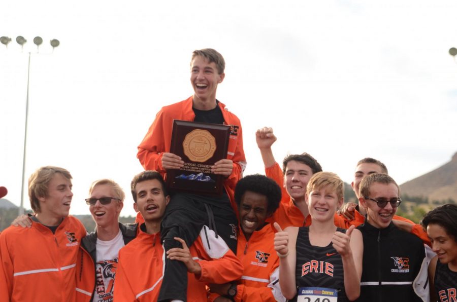 Luke Fritsche being held up by the cross country team with teams trophy after winning regionals