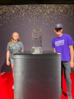 Parker Driscoll and Emilee Newton standing next to the World Series Trophy